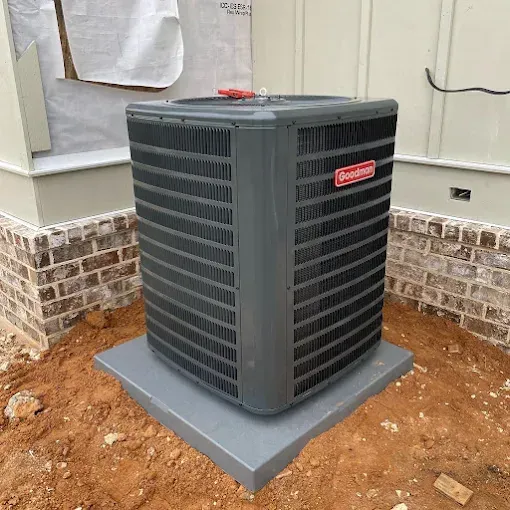 Outdoor HVAC unit on a gray concrete pad beside a brick house foundation