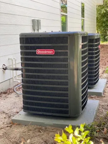 Two Goodman outdoor HVAC units beside a house on a concrete pad