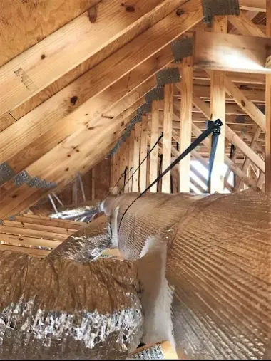 Attic with exposed wooden rafters and insulation covering the floor and sloped ceiling