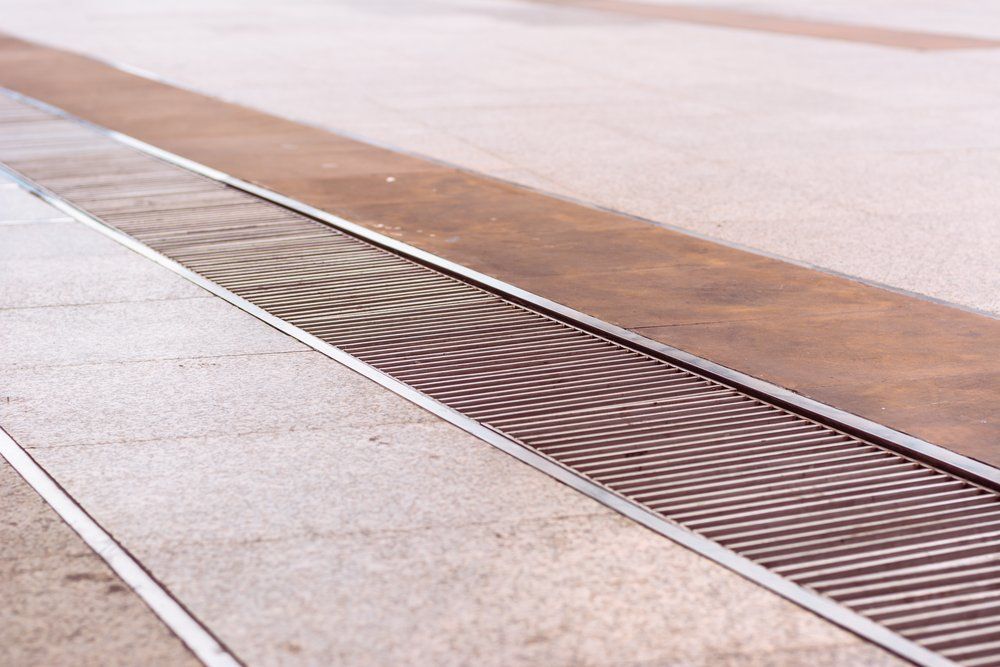 A close up of a metal drain on a sidewalk.