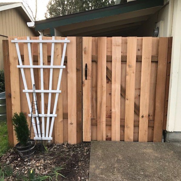 Wooden fence with a white trellis and gate.