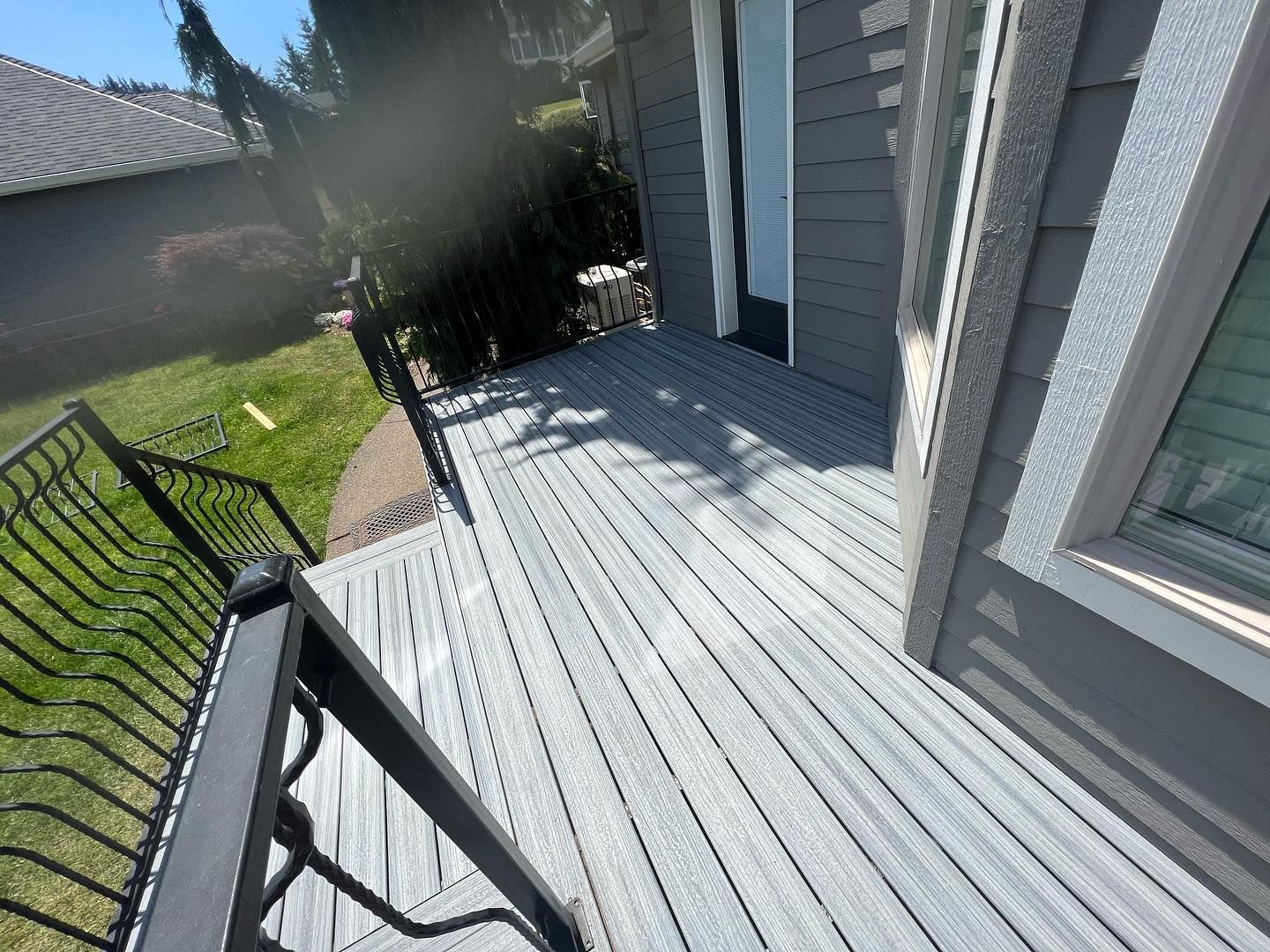 Gray composite deck with black railing next to a gray house.