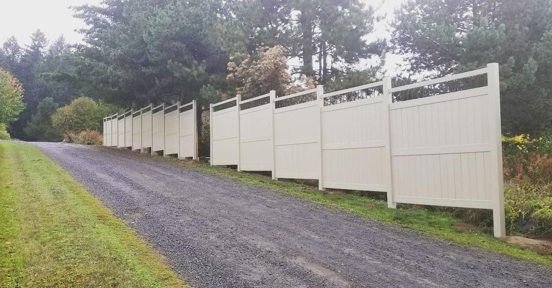 White vinyl fence bordering a gravel driveway.