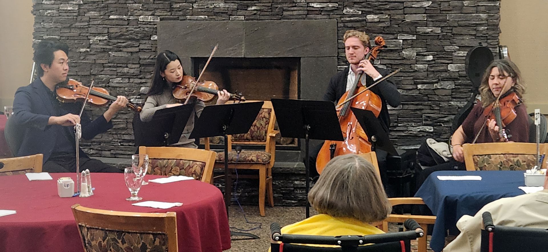 A group of people are playing violins and cello in a room.