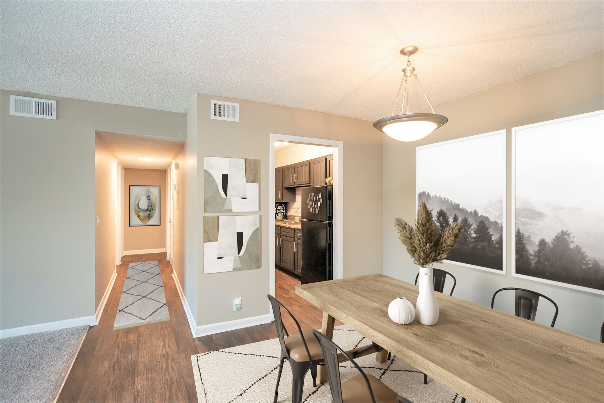 A modern apartment dining area with a wood table, metal chairs, and a hallway leading to a kitchen.
