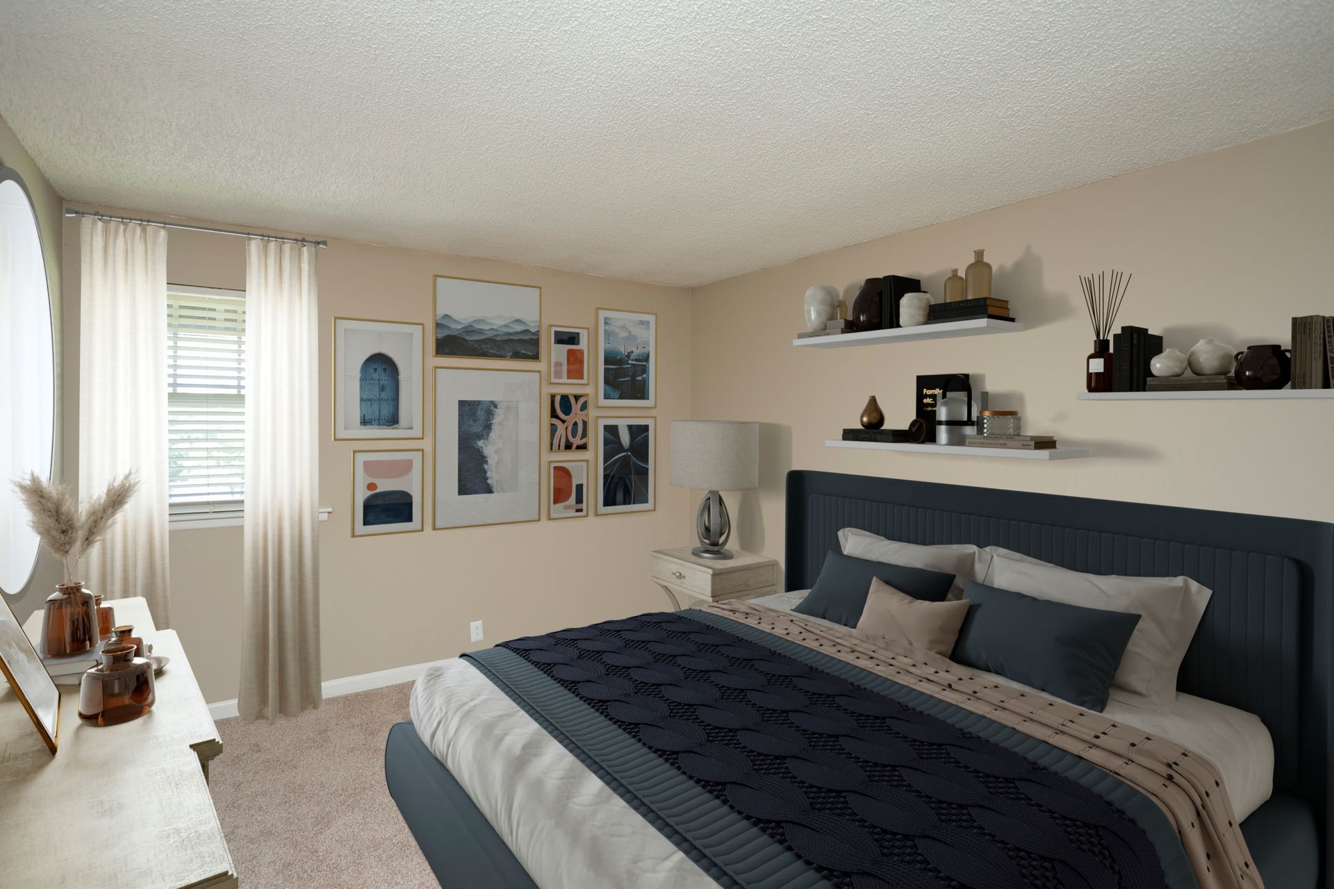 A bedroom with a dark blue upholstered bed, gallery wall art, light curtains, and shelving on a soft beige wall.