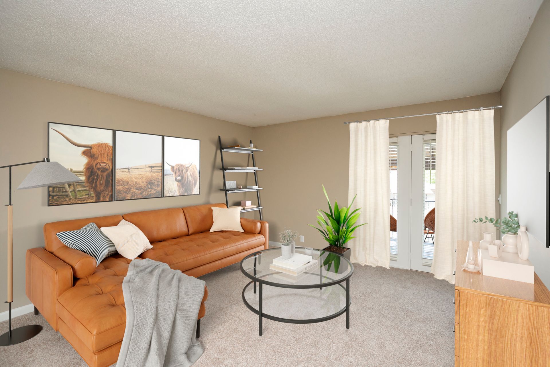 A modern living room with a tan leather sectional, a glass coffee table, shelving, and sliding glass doors with curtains.