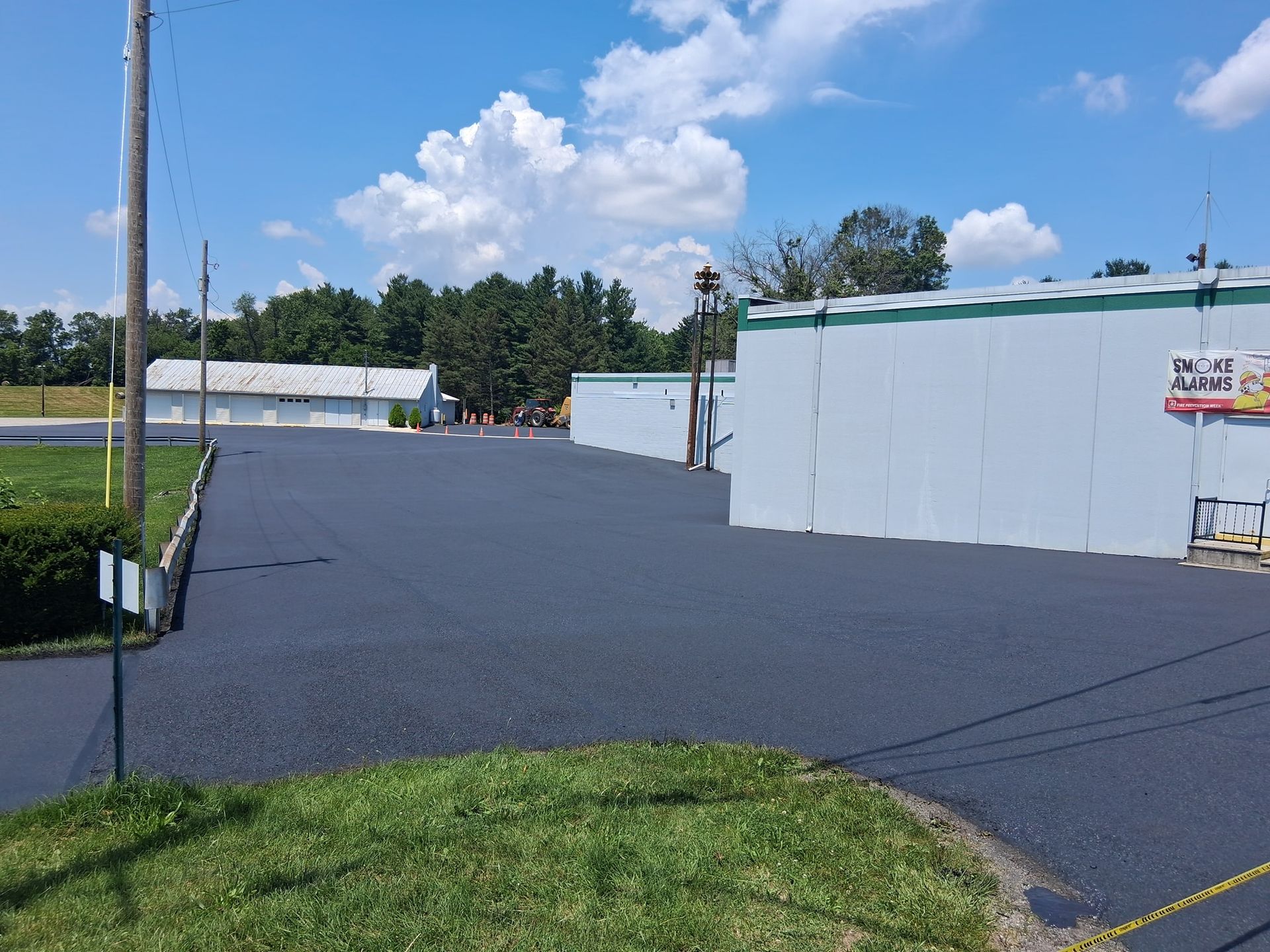 Newly paved asphalt lot next to a white commercial building under a blue sky.
