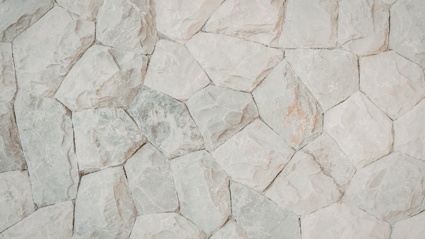 A close-up of a wall made of irregularly shaped, light gray stone blocks with visible textures and mortar joints.