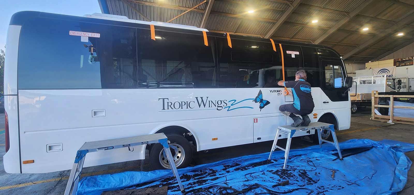 A Man is Repairing a Coach Window  — FNQ Windscreens in Bungalow, QLD