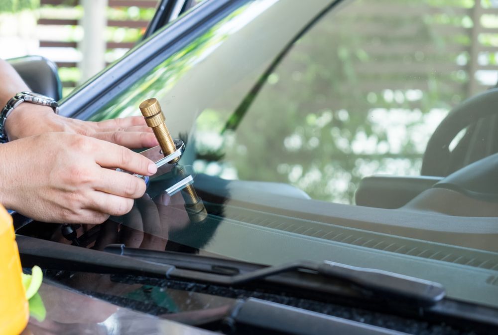 A Person is Fixing a Broken Windshield on a Car — FNQ Windscreens in Bungalow, QLD