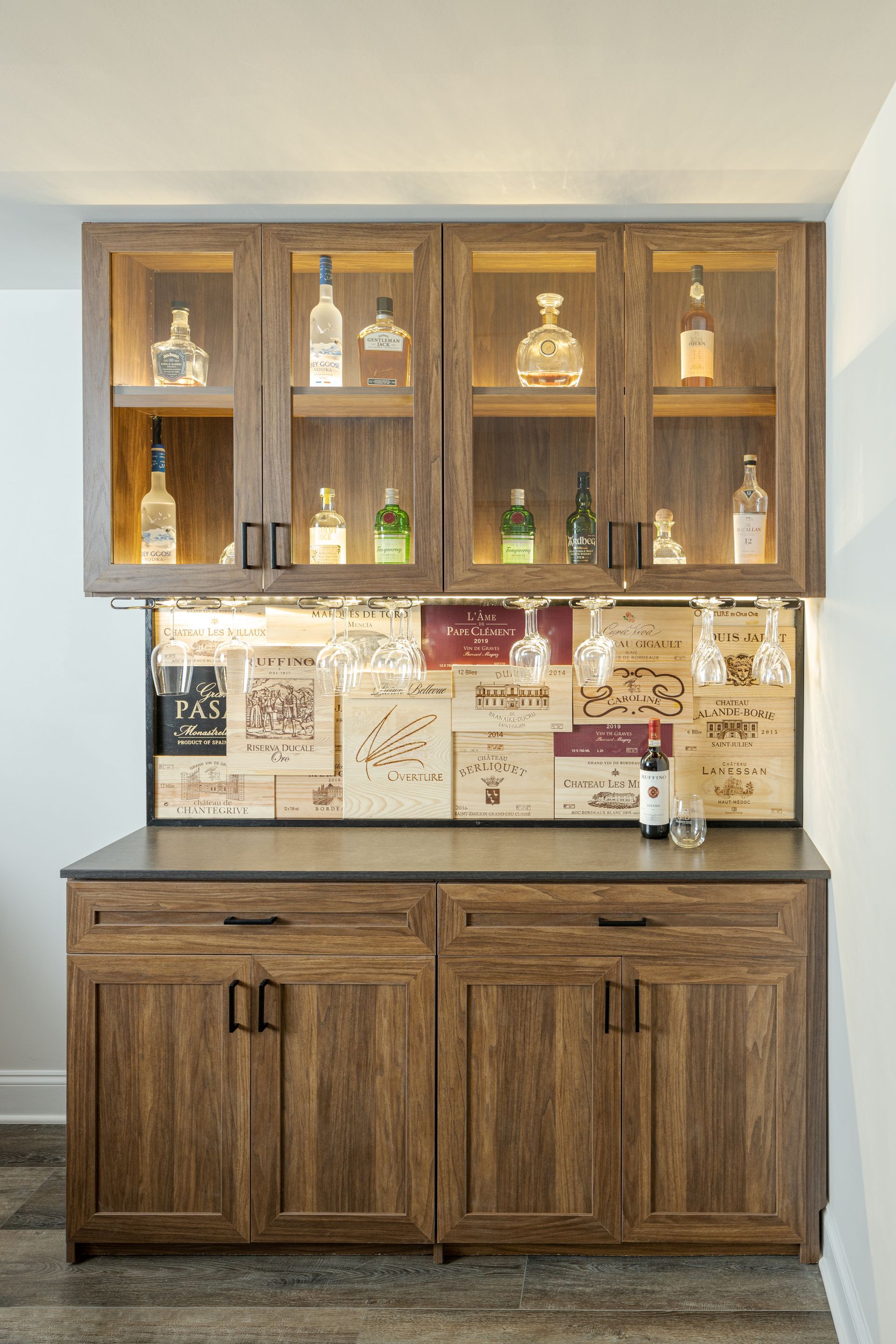 Wooden display cabinet with glass shelves and decor above a matching sideboard in a neutral room