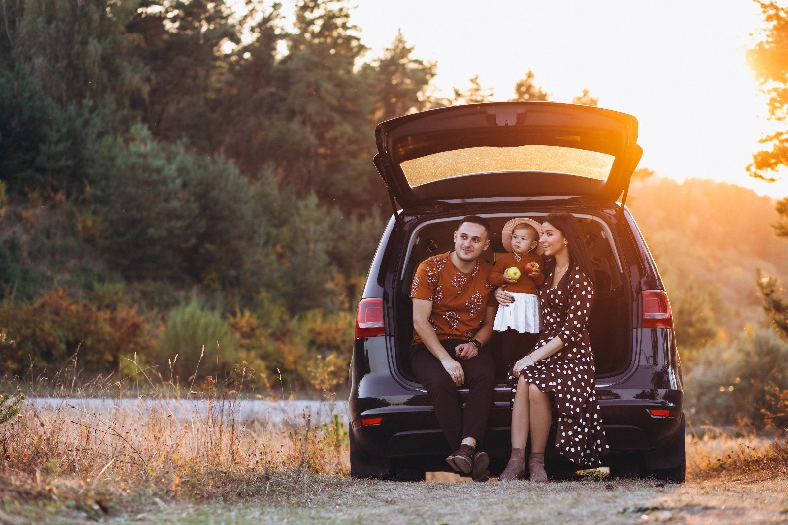A family sitting in the open trunk of a dark SUV after getting the back glass replaced at Auto Glass 2020