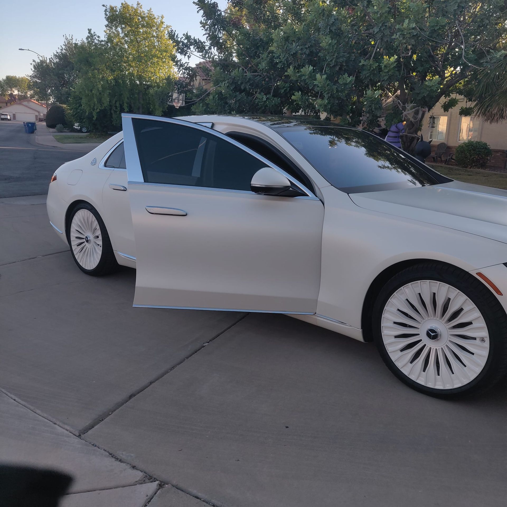 A white car with the door open is parked on the side of the road