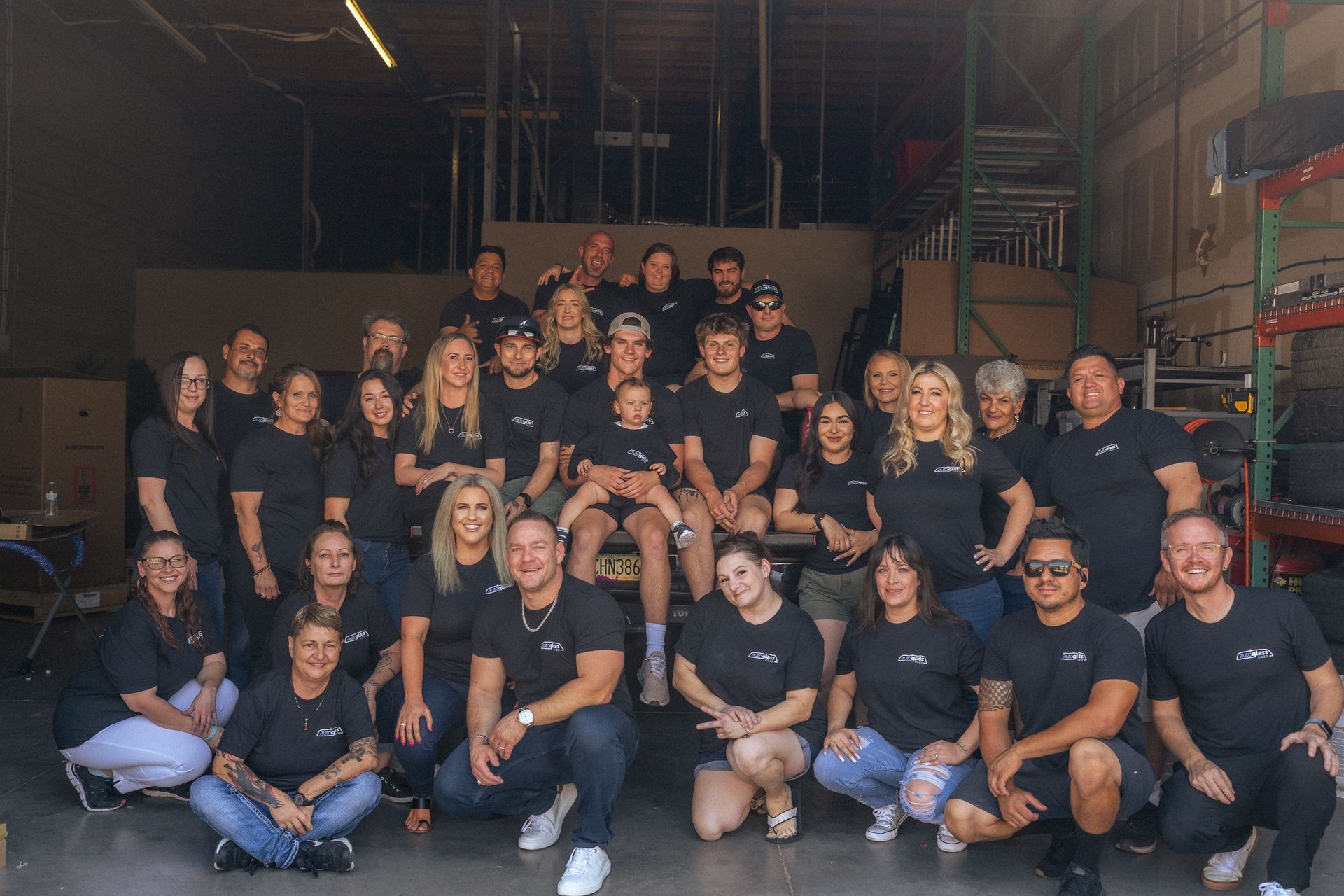 A large group of people are posing for a picture in a warehouse.