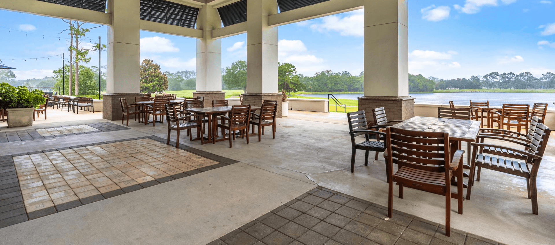 Outdoor patio with tables and chairs overlooking a lake.