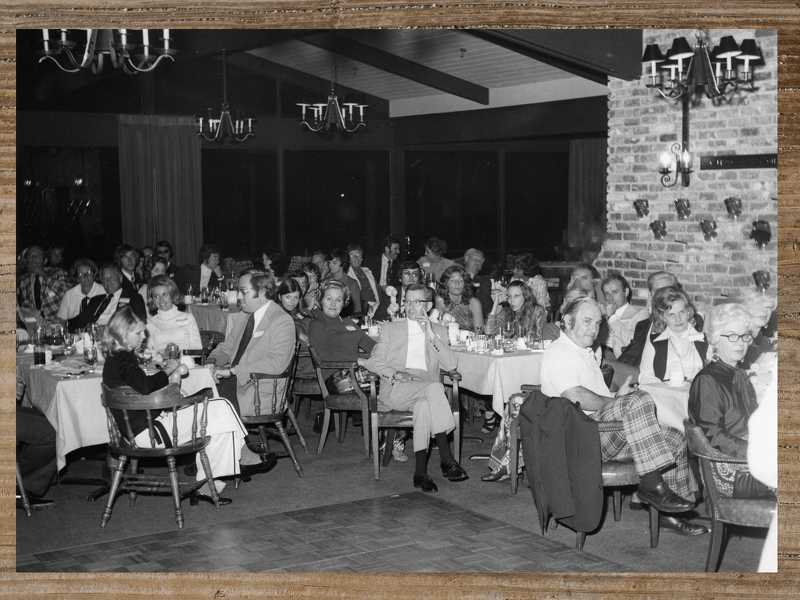 People seated at tables in a dimly lit restaurant, likely a gathering.