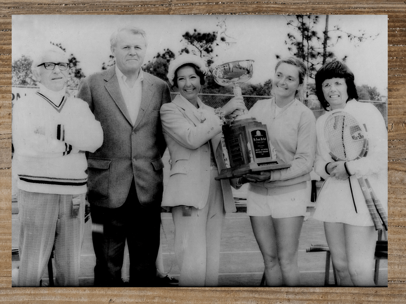 Group of people pose with a large trophy outdoors.