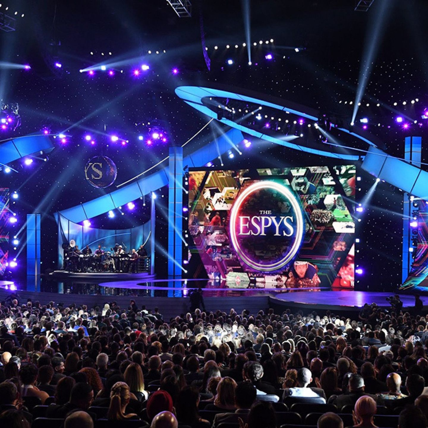 Packed arena at the ESPYS awards stage glowing blue and purple, with a large central screen and audience in front