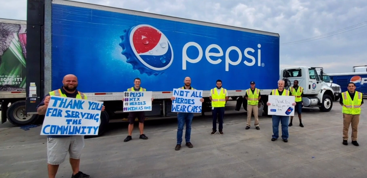 Protesters holding signs in front of a Pepsi truck in a parking lot.