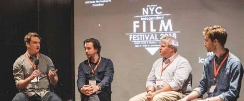 Four men on a panel at NYC Film Festival, seated onstage in front of a logo backdrop