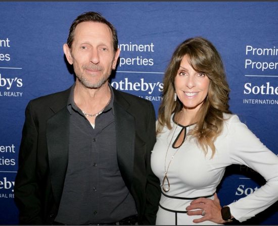 Two people posing in front of a Sotheby’s step-and-repeat backdrop, smiling at a formal event.
