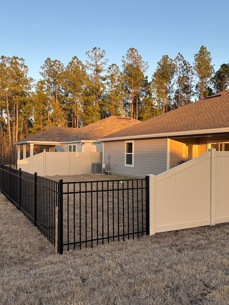 Single-story house with black metal fence and beige privacy gate at sunset