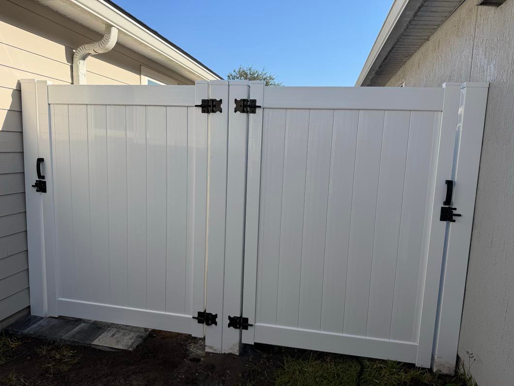 White double wooden gate between two beige houses under a blue sky