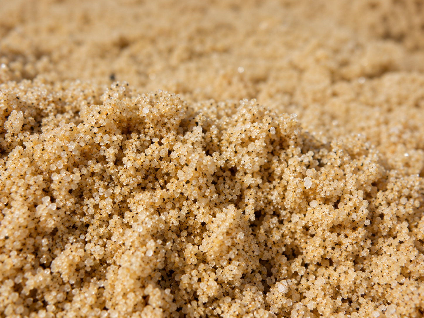 Close-up of beige sand grains forming small ridges and mounds.