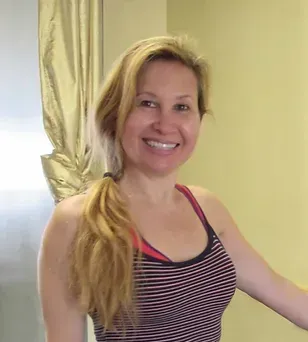 A woman in a striped tank top is smiling in front of a mirror.