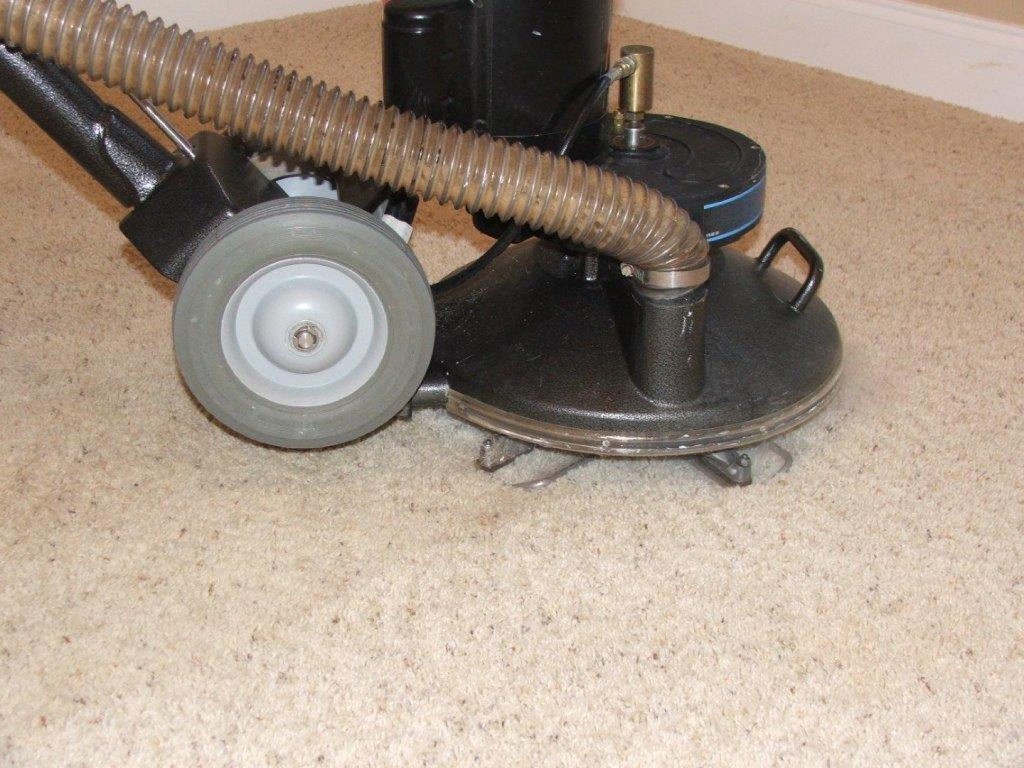 Floor buffer with gray wheels and hose on beige carpet