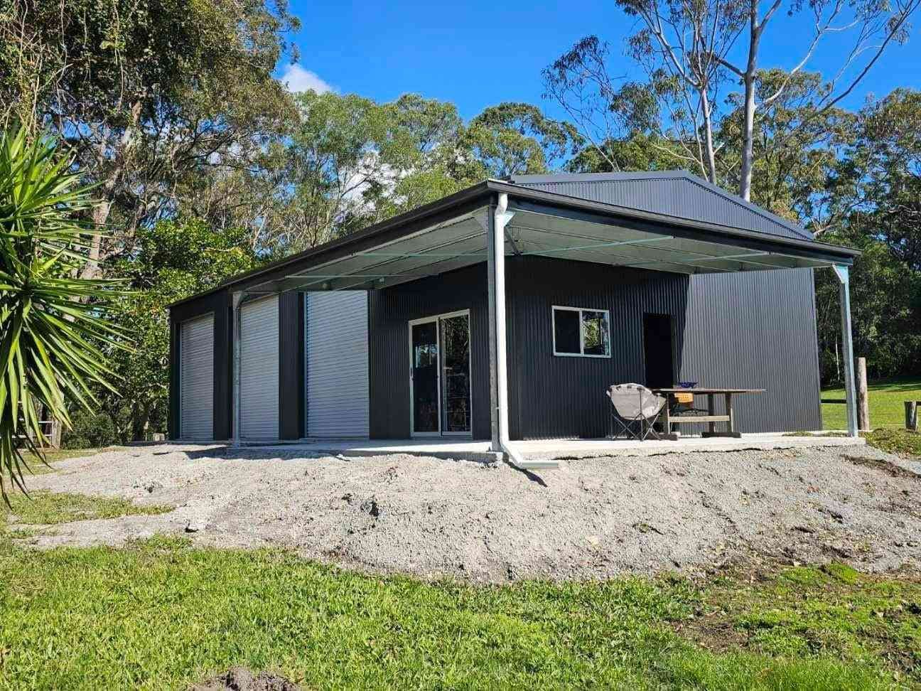 Dark Gray Cabin With a Covered Porch, Set in a Grassy Area With Trees in the Background — North Coast Sheds & Garages in Coraki, NSW