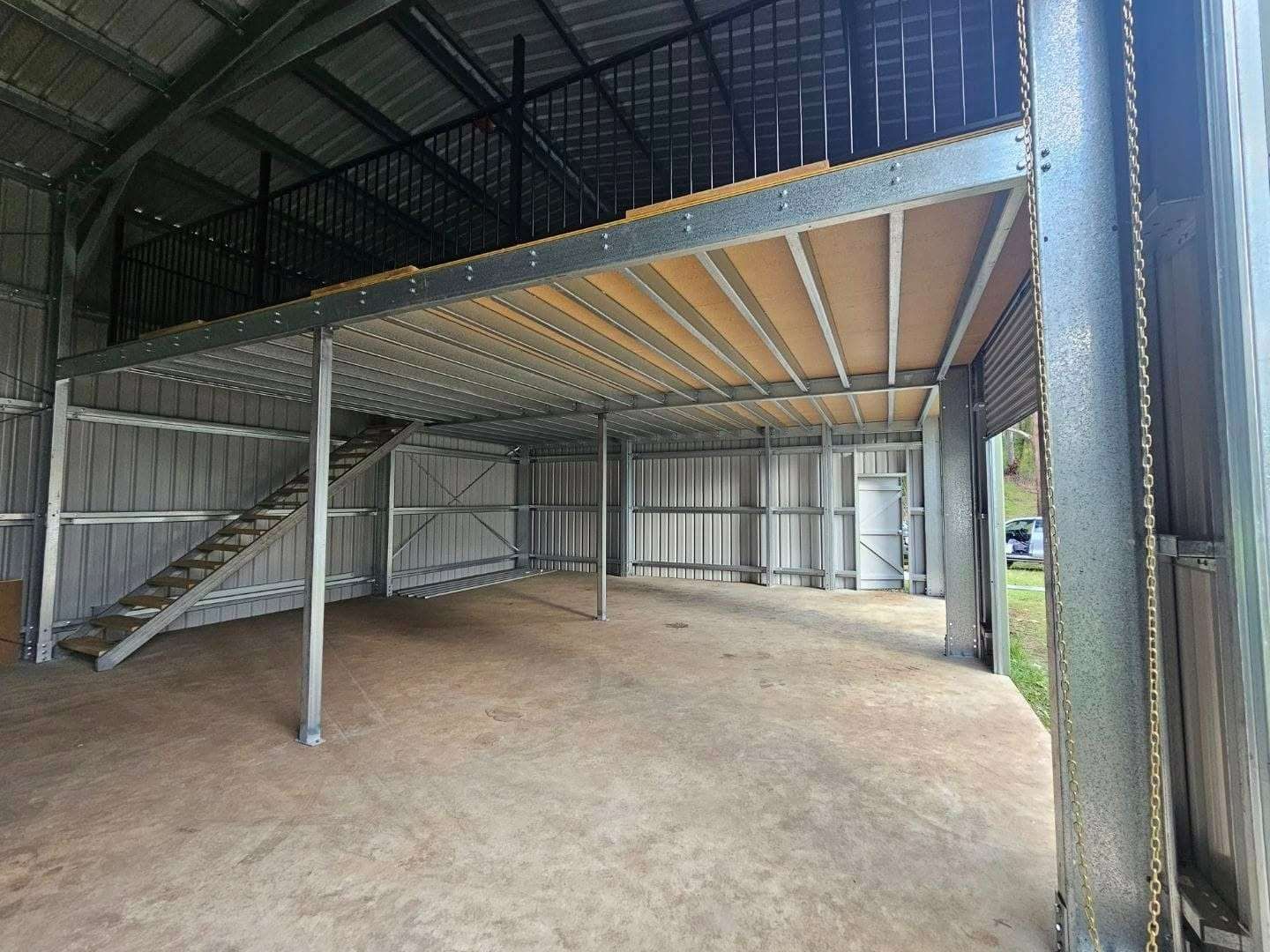 Interior View of a Metal Shed With a Built-in Mezzanine. Gray Metal Structure, a Wooden Staircase, and Corrugated Metal Walls and Roof — North Coast Sheds & Garages in Coraki, NSW