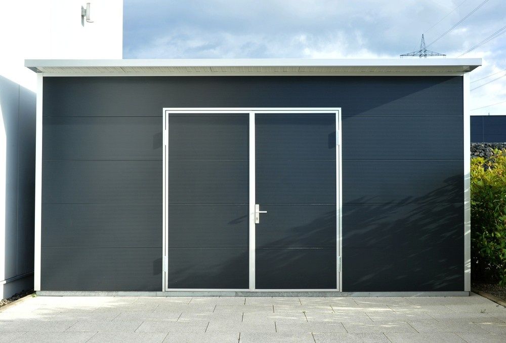 A Dark Gray Shed With Double Doors, Silver Trim, and a Flat Roof, Set on a Paved Area — North Coast Sheds & Garages in Yamba, NSW