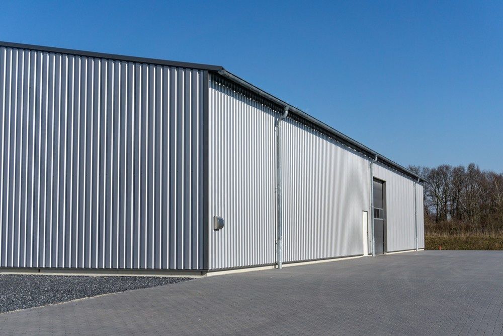 Silver Corrugated Metal Building With a Black Trim and a Door Against a Clear Blue Sky — North Coast Sheds & Garages in Yamba, NSW