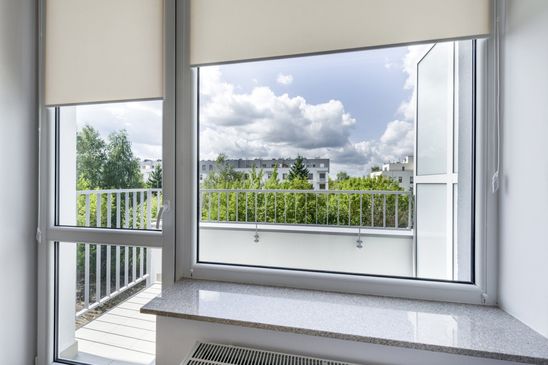 Grey toned laundry over looking fenced balcony, roller blinds rolled half way up for external view.