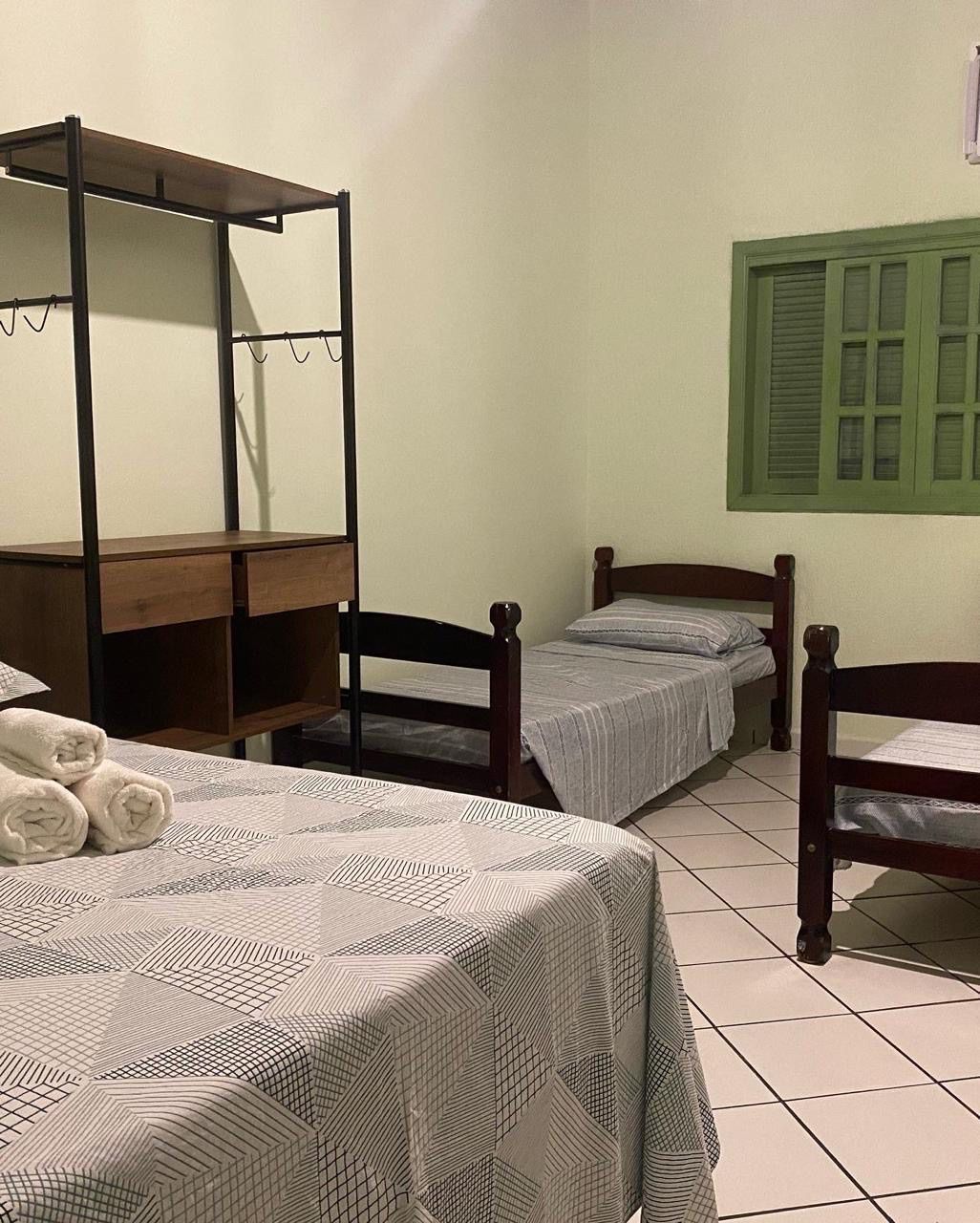 Um quarto com duas camas, um armário e uma janela. Pousada Meraki