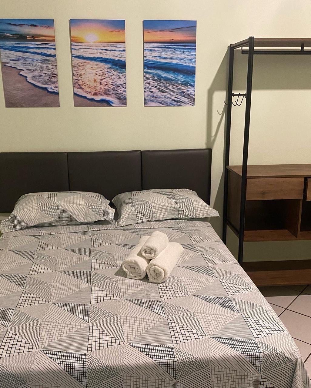 Há três pinturas na parede acima da cama. Pousada Meraki