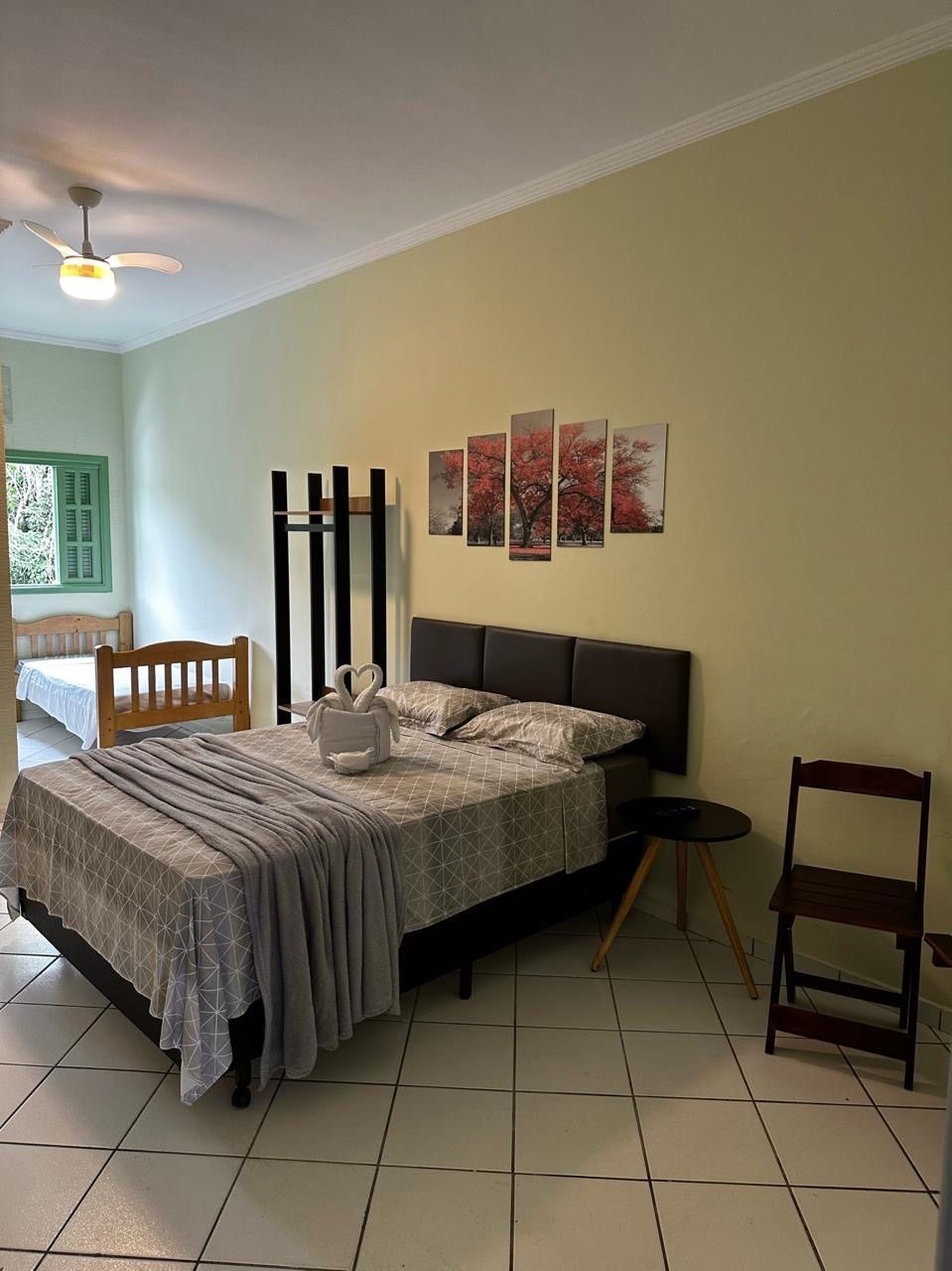 Um quarto com cama, cadeira, mesa e ventilador de teto. Pousada Meraki