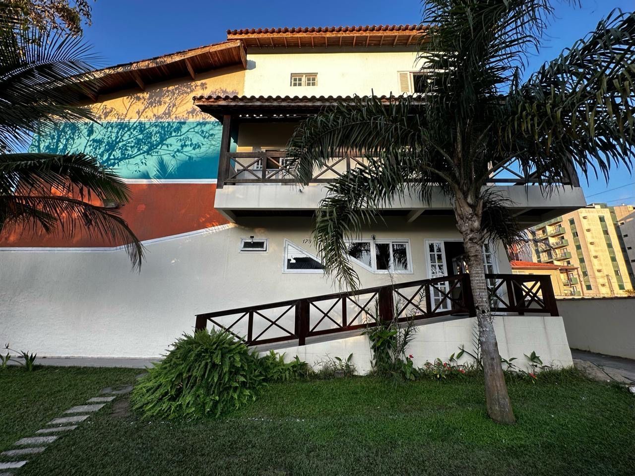 Uma casa grande com uma escada que leva até ela e uma palmeira na frente dela. Pousada Meraki