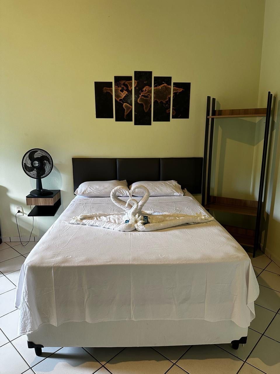 Um quarto com uma cama, um ventilador e um mapa na parede. Pousada Meraki