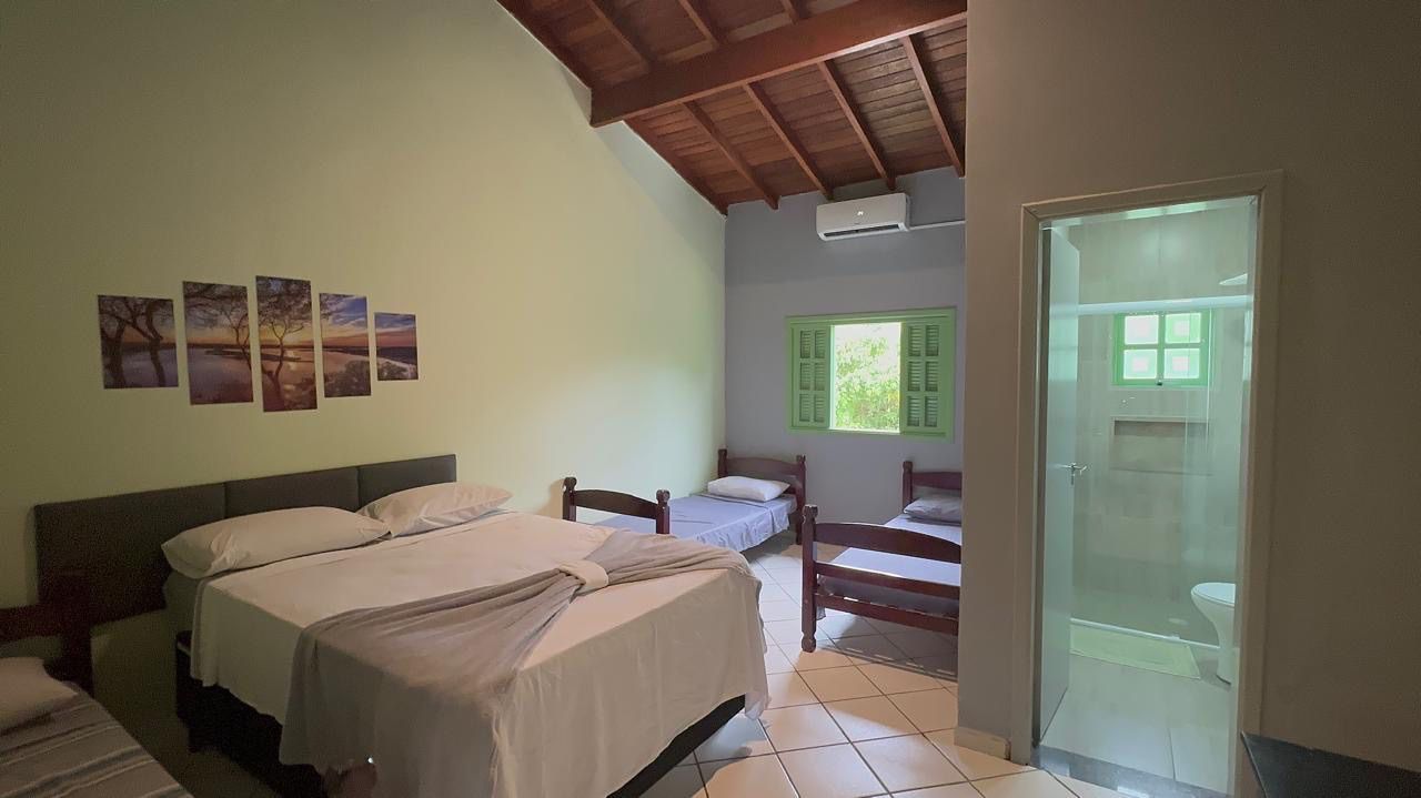 Um quarto com uma cama king size, duas camas de solteiro e um banheiro. Pousada Meraki