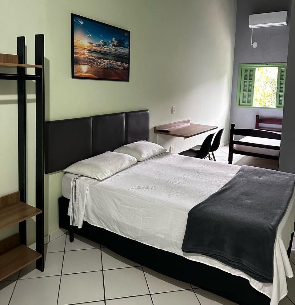 Um quarto com uma cama grande e um quadro na parede acima dela Pousada Meraki