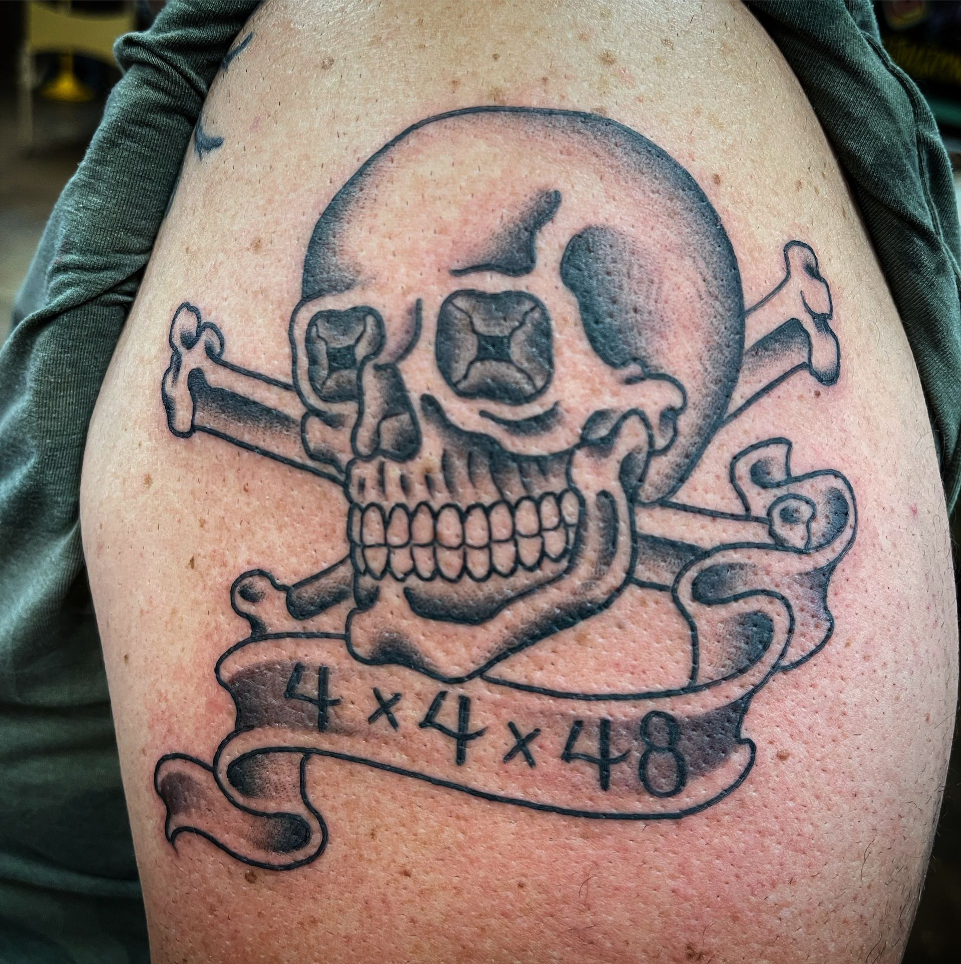 Tattoo of a skull and crossbones with a banner reading 