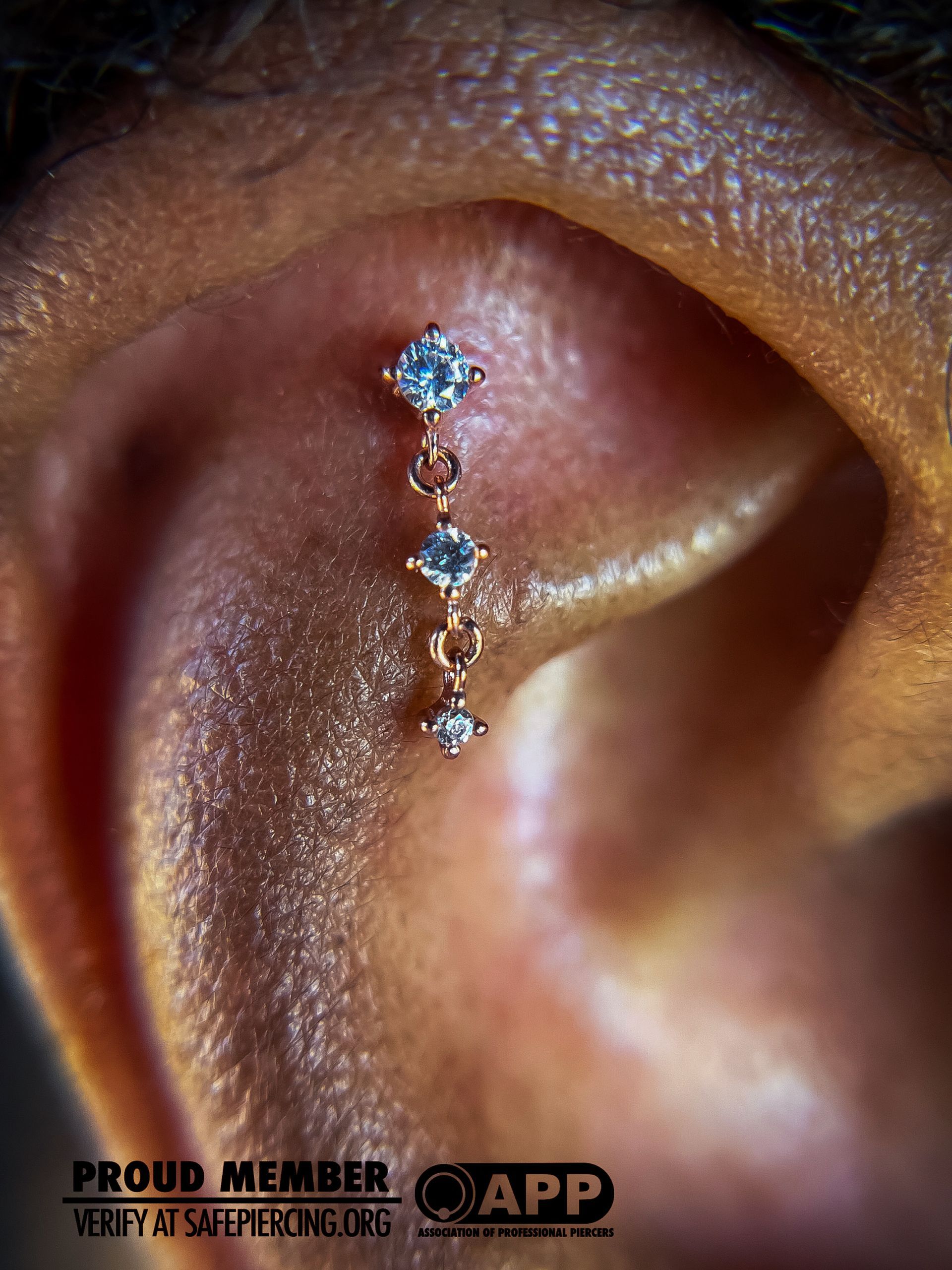 Close-up of a gold ear cuff with blue gemstones on a human ear