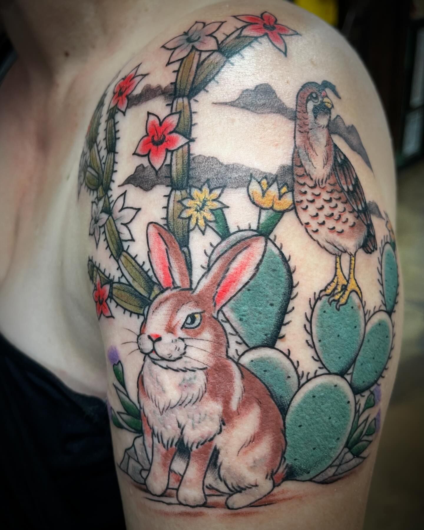 A woman has a tattoo of a rabbit and a bird on her shoulder