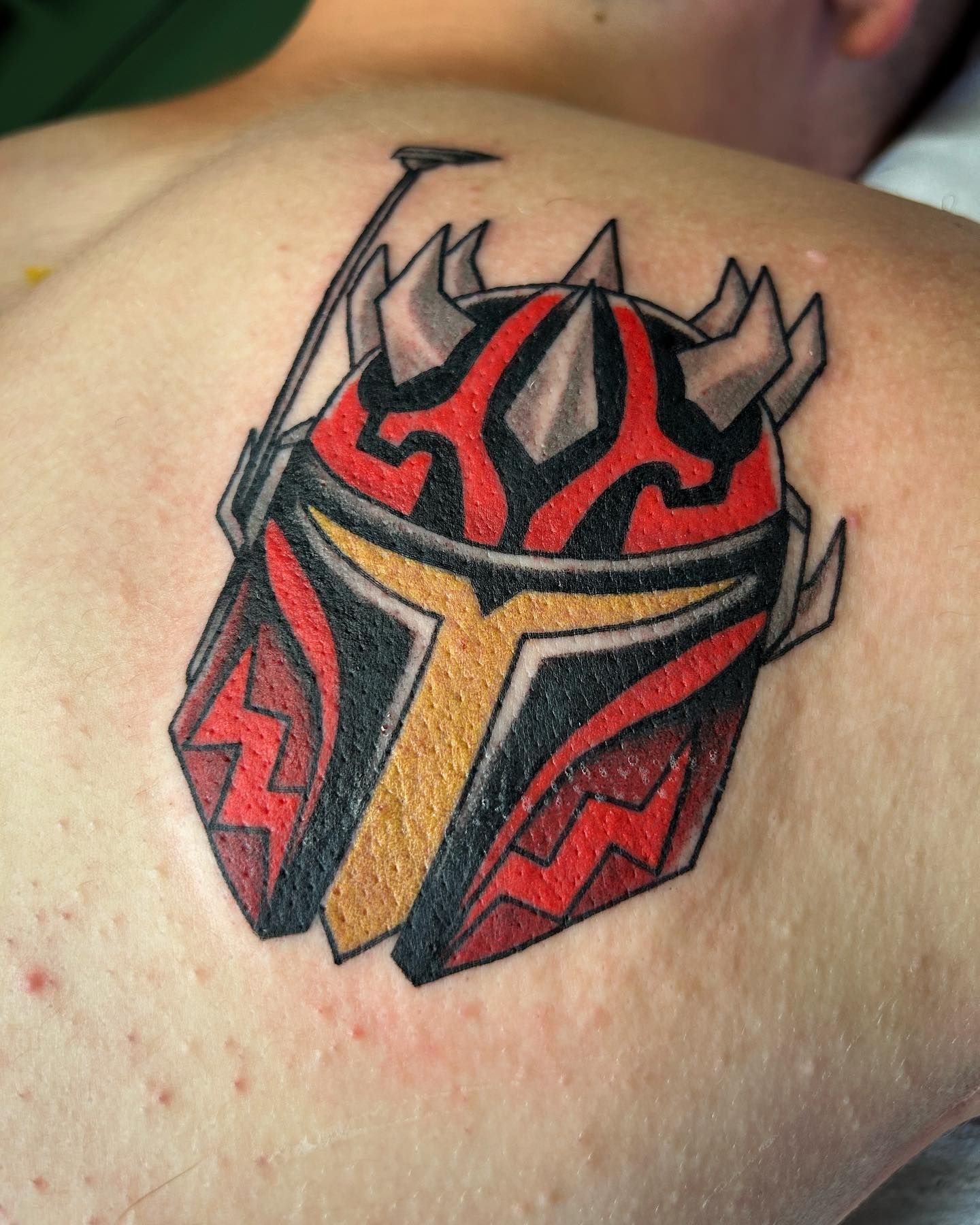 A person has a tattoo of a helmet on their back