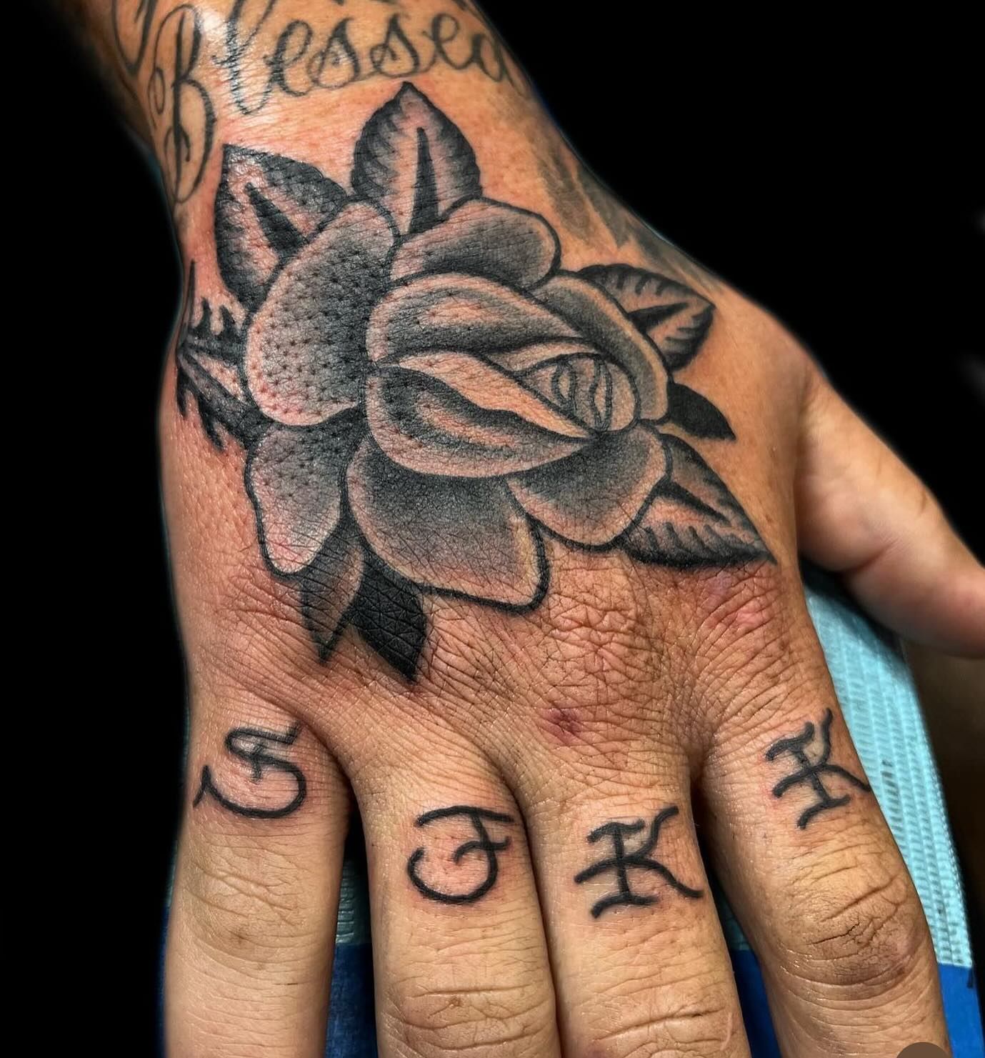 A man has a tattoo of a rose on his hand.