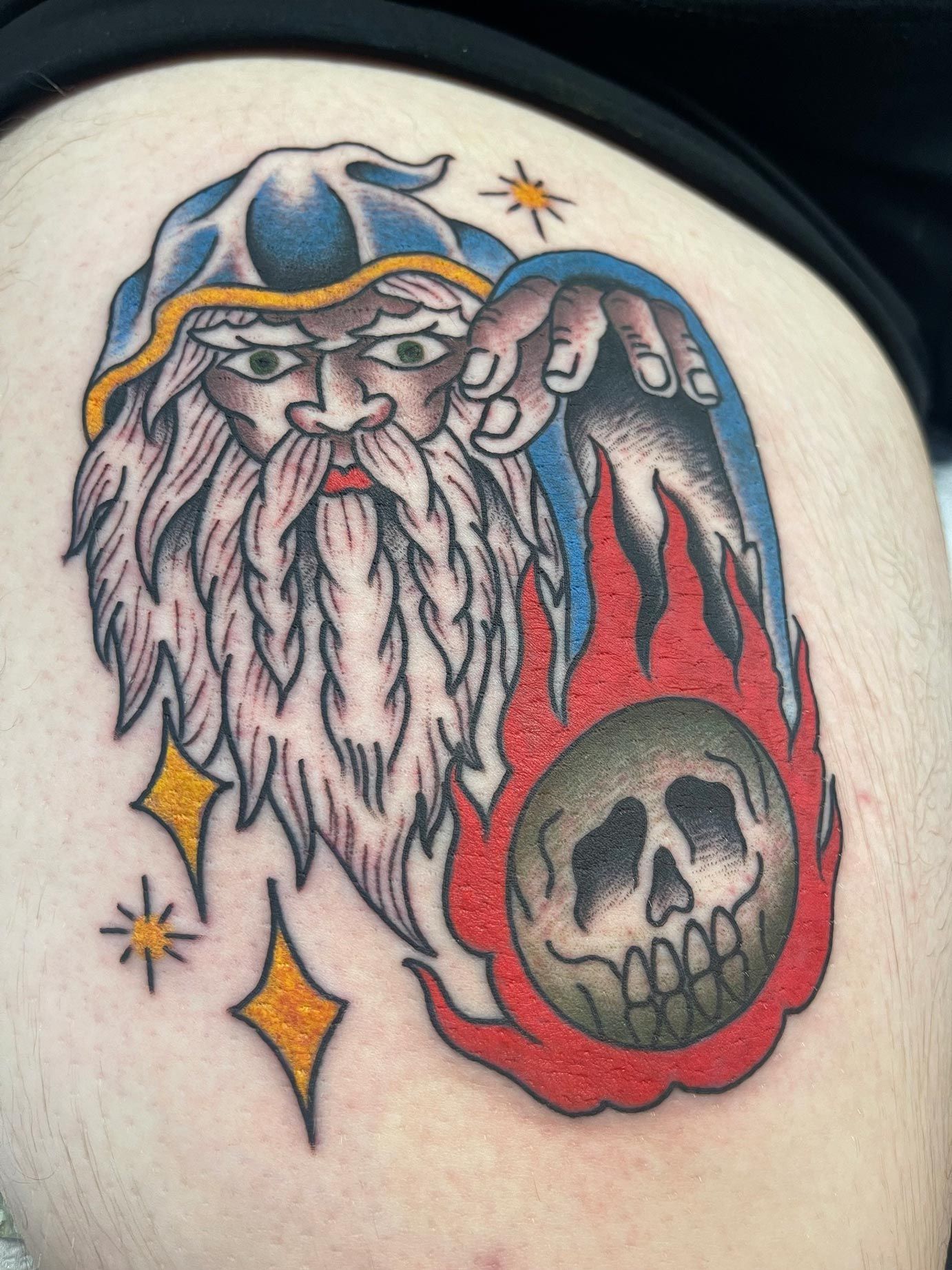 A tattoo of a man with a beard holding a skull