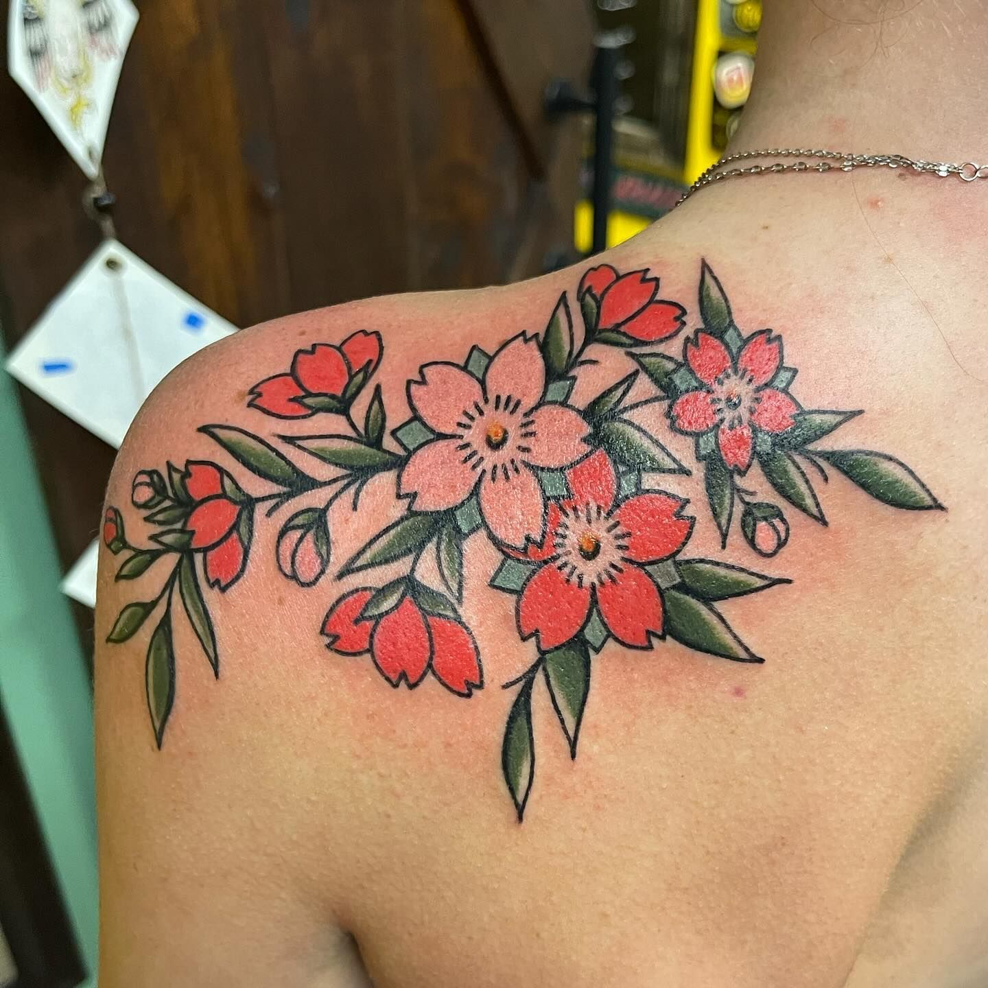 A woman has a tattoo of red flowers on her shoulder